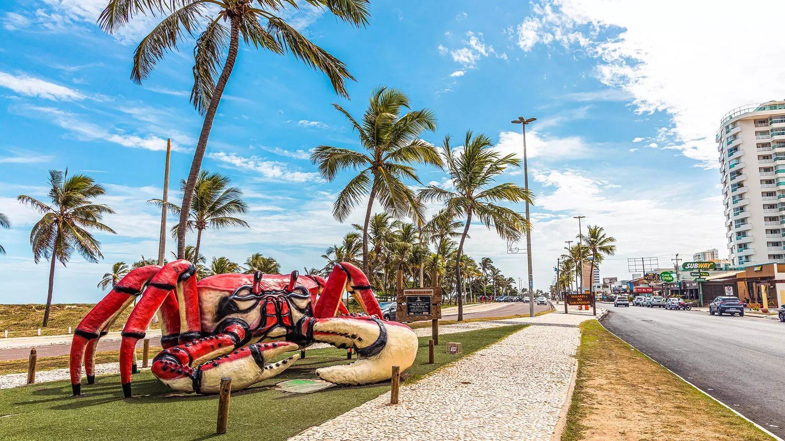 Orla de praia ao entardecer com calçadão e coqueiros em Aracaju, Sergipe