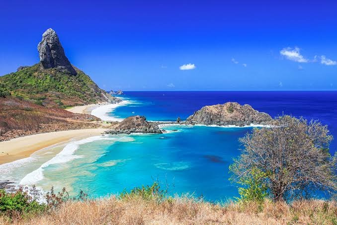 Praia paradisíaca com águas cristalinas e morros ao fundo em Fernando de Noronha