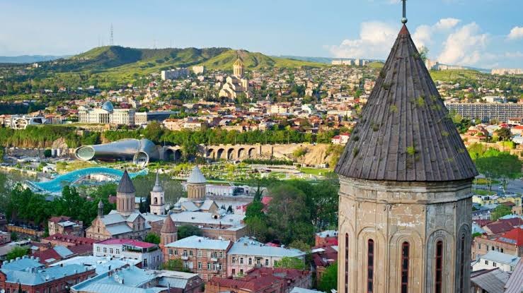 Vista aérea de Tbilisi, capital da Geórgia, com torre histórica e cidade ao fundo